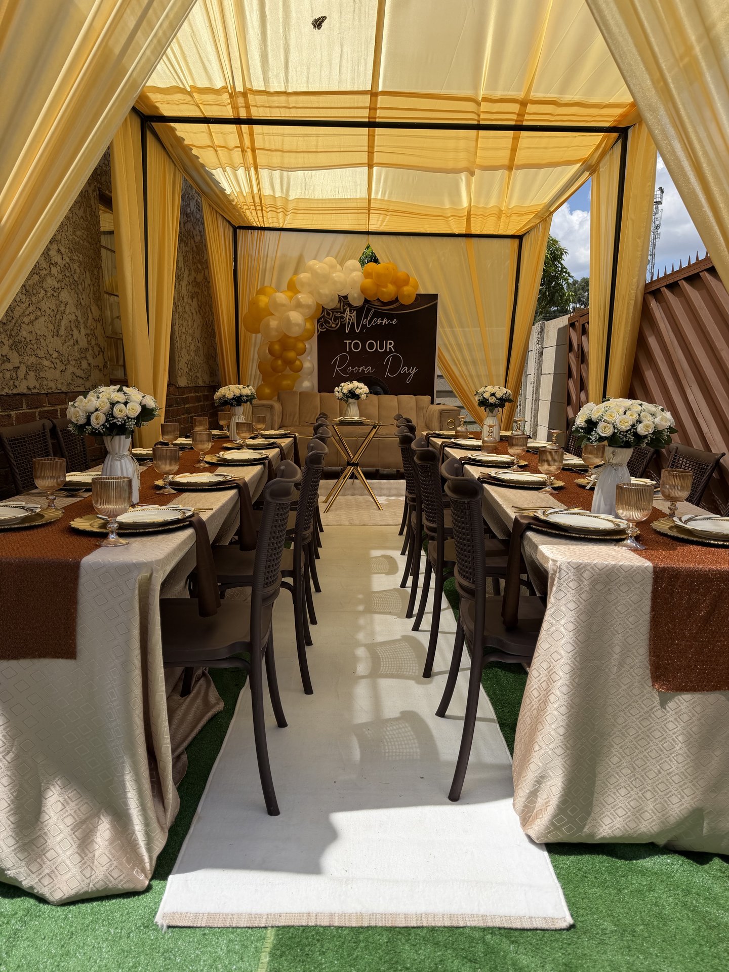 Gold canopy picnic setup with a long table and floral centerpieces, styled by Triumphant Events