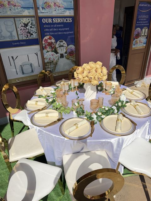 Round table with gold chargers, a white floral centerpiece and folded napkins, by Triumphant Events
