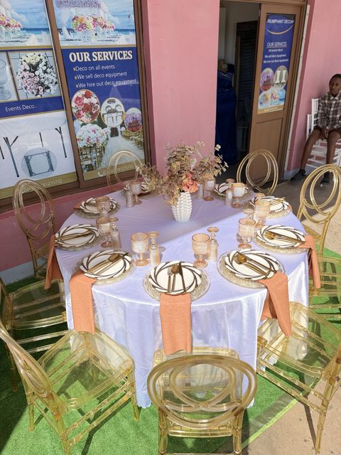 Round table with a peach linen runner, gold-rimmed plates and gold chiavari chairs, by Triumphant Events