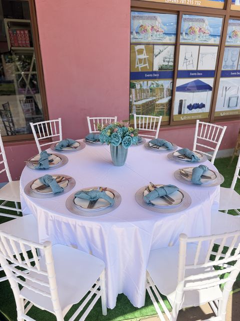 Close-up of a teal and white table setting with gold chargers and folded napkins
