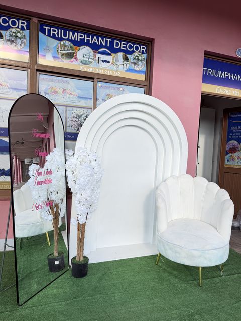 White arch backdrop with mirror and velvet chair, displayed in the showroom