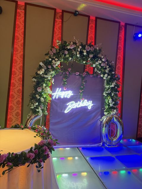 Floral arch with a "Happy Birthday" neon sign over a colour-changing LED dance floor, by Triumphant Events