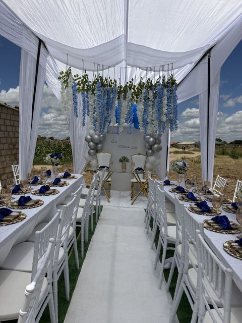 Blue and silver wisteria-draped tent aisle with navy table settings, by Triumphant Events
