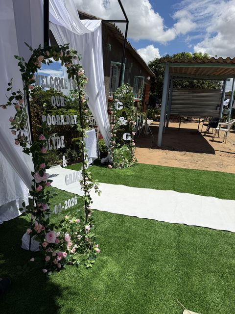 "Welcome to Our Rooraday" mirror sign with a rose garland, along a white aisle runner
