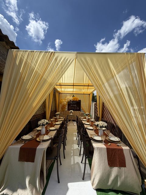 Gold-draped dinner tent with a long reception table, by Triumphant Events