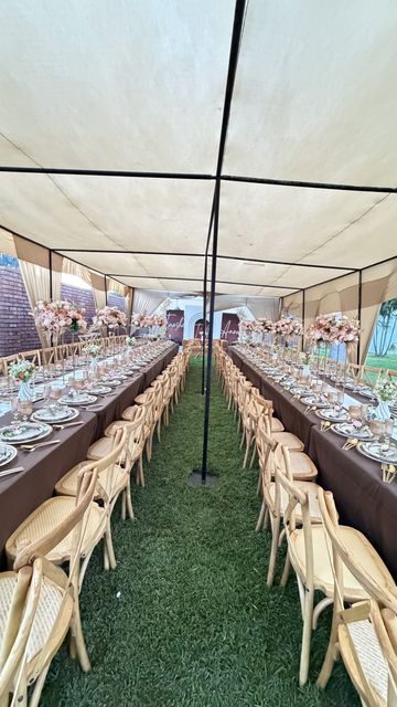Long tent reception table with tall floral centerpieces and gold place settings, by Triumphant Events
