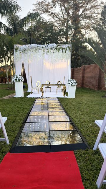 Mirror-tiled aisle with a red carpet runway leading to a wisteria-draped sweetheart table