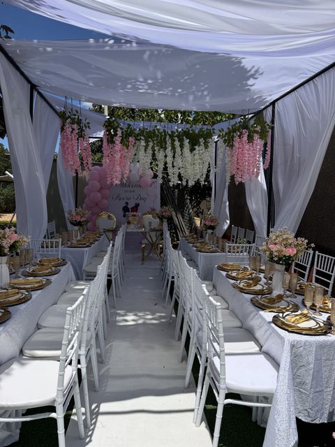 Pink and blue wisteria-draped tent aisle with gold chiavari chairs, by Triumphant Events