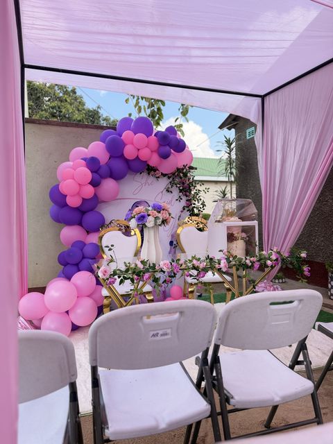 Close-up of a purple and pink balloon garland arch at a garden picnic