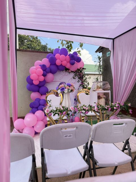 Purple and pink balloon garland arch at a garden picnic setup, by Triumphant Events
