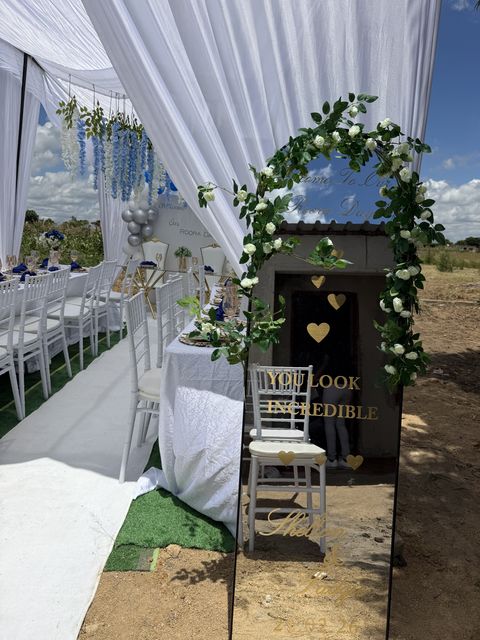 White-draped tent entrance with a floral arch, by Triumphant Events