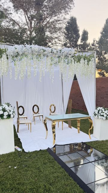 White wisteria-draped teepee backdrop with a sweetheart table, set up at dusk